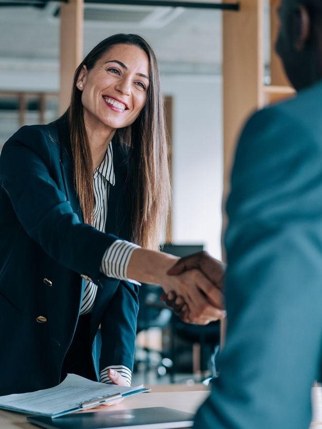 Business people shaking hands in the office during a meeting, with a female manager discussing a new project with her colleagues.
